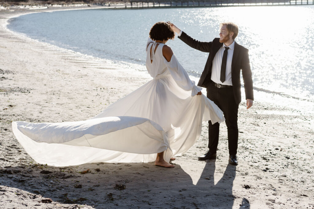 A couple twirling on the shore of a lake on their elopement day in Washington. 