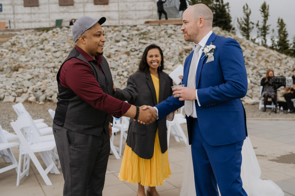 The groom shakes hands with a wedding guest after the ceremony.