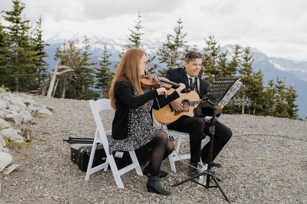A live music duo plays the violin and guitar after the wedding ceremony atop Crystal Mountain. 