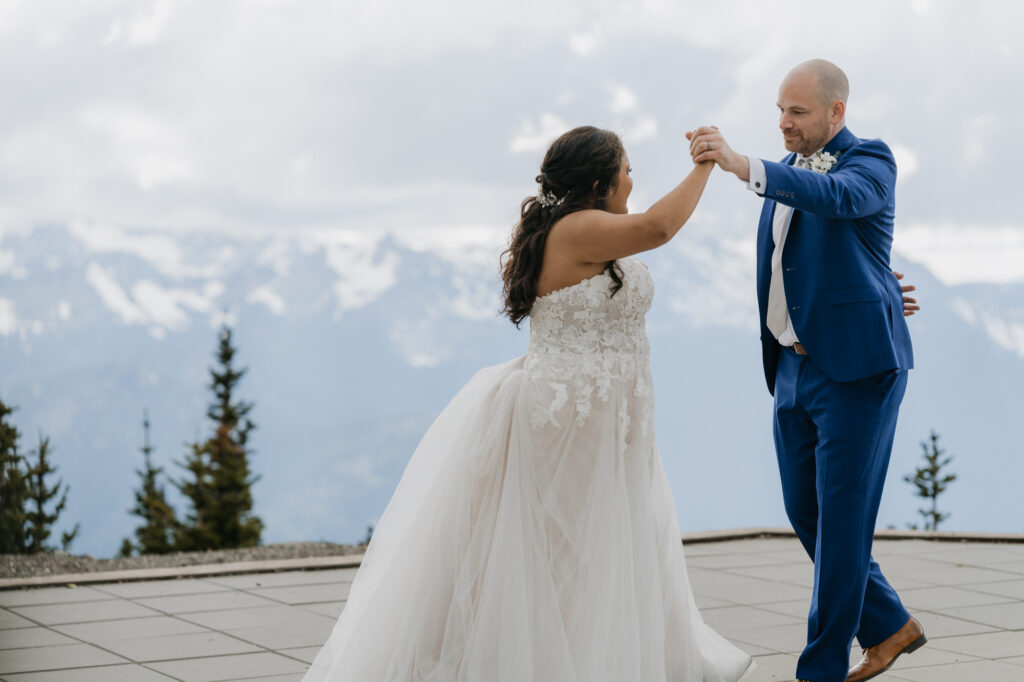 A groom twirls his bride while they dance atop the Mt. Rainier Platform at Crystal Mountain in Washington State. 
