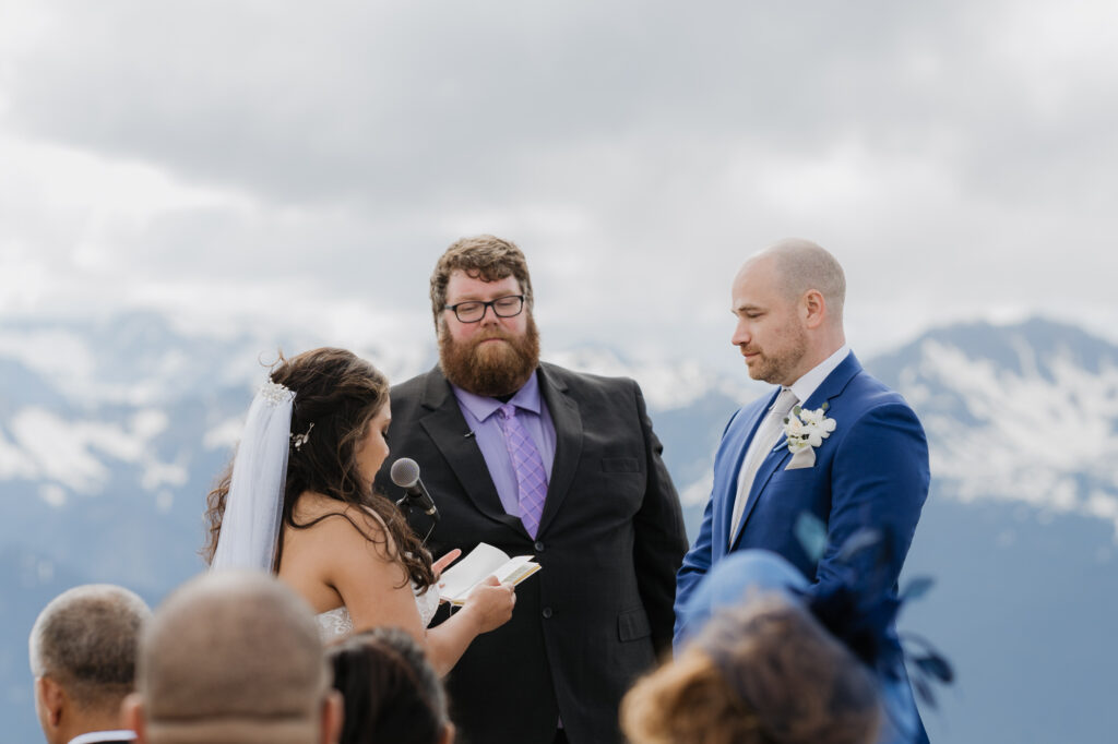 A bride reads her vows to the groom while standing atop Crystal Mountain in Washington State. 