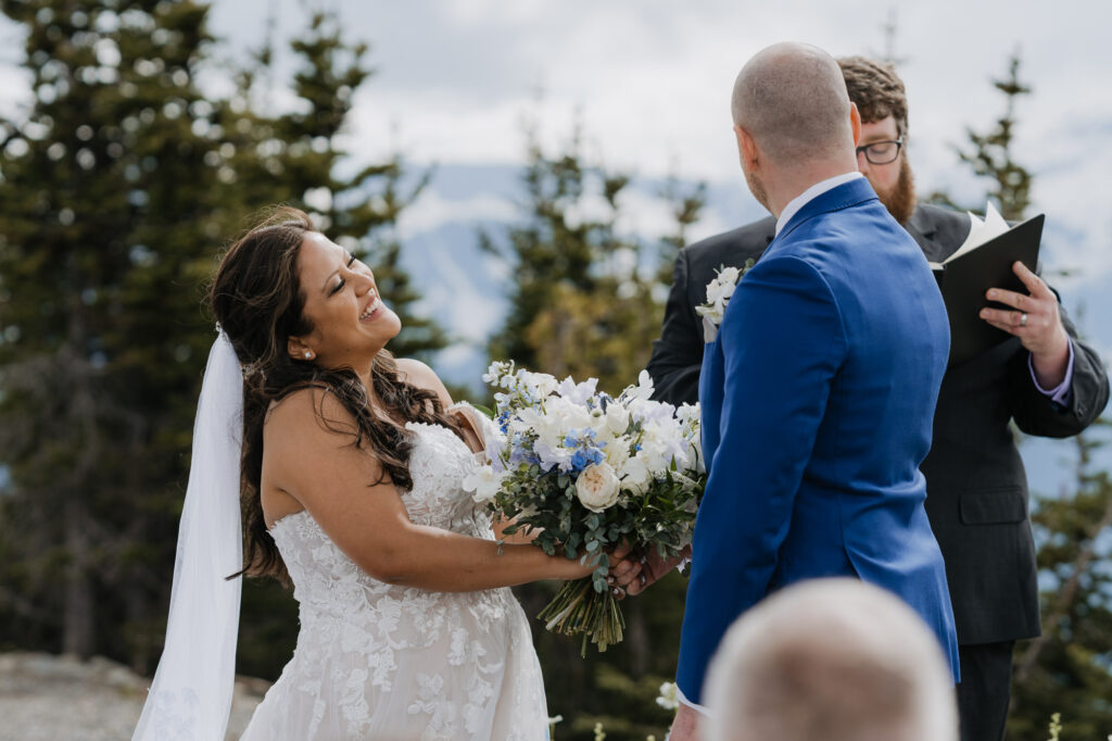 A bride smiles at her groom while standing at the alter of their wedding ceremony with a view of Mt. Rainier national park in the background. 