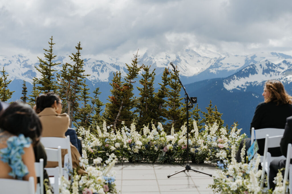 A view from the wedding ceremony space at the Mt. Rainier Platform within Crystal Mountain resort. There are guests and a floral arrangement in the photo.