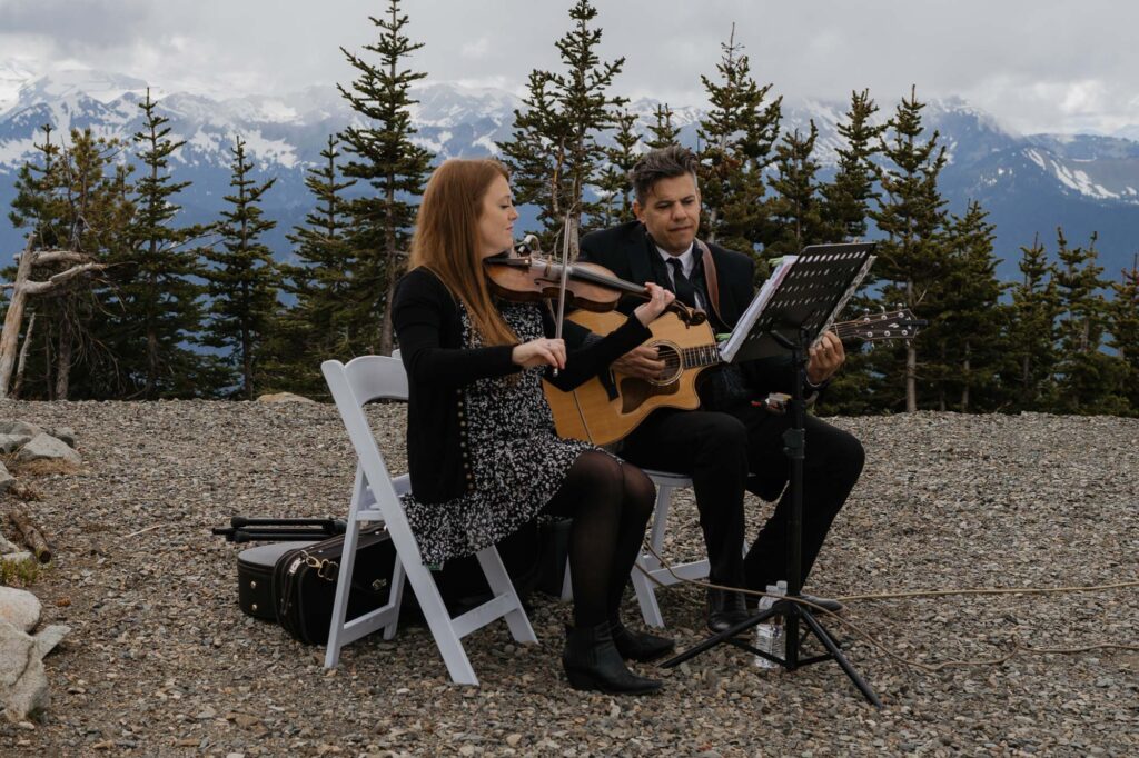 A music duo playing the violin and guitar before a wedding day ceremony at Mt. Rainier National Park in Washington State. 