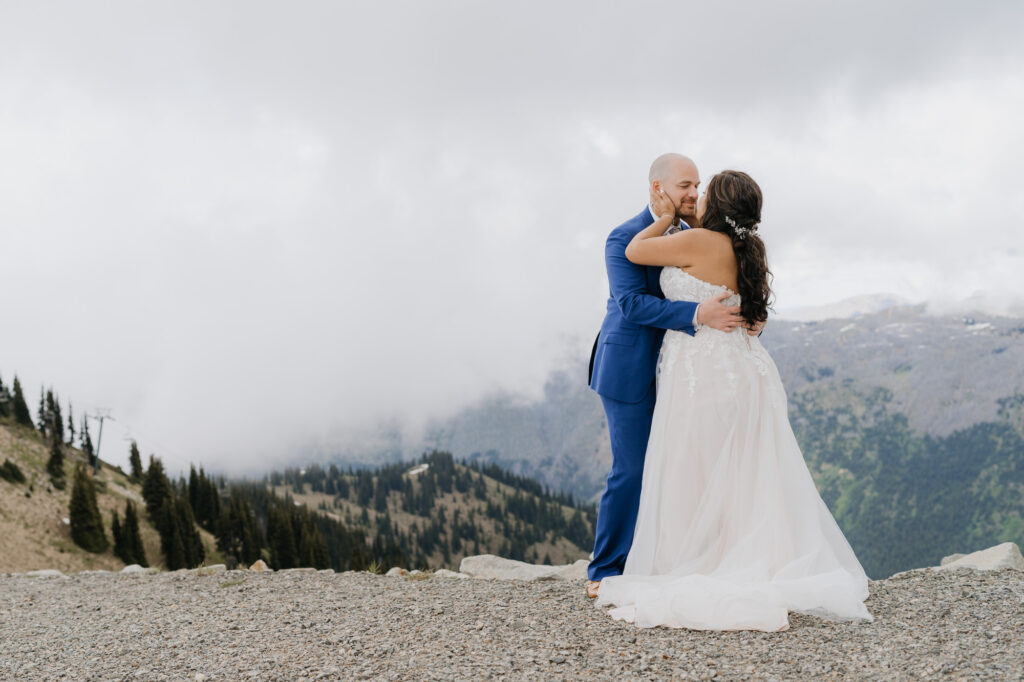 An intimate wedding atop Crystal Mountain near Mt. Rainier national park. The couple is embracing each other with mountain views in the background.