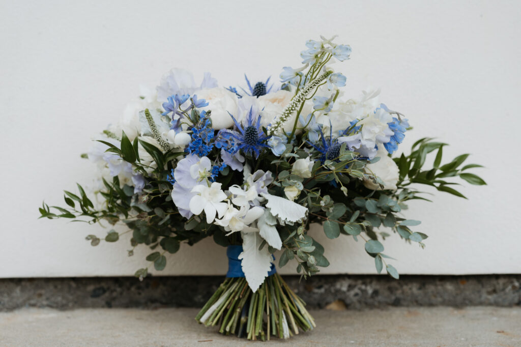A close up photo of the brides bouquet full of white, purple, and blue flowers.