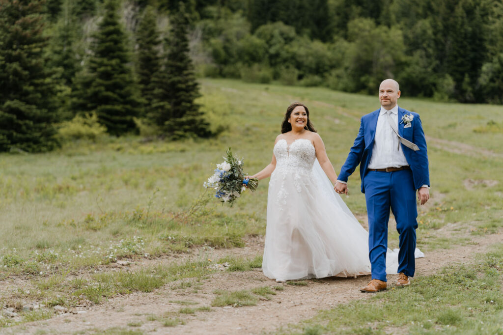 A bride and groom smile while walking along the hillside at Crystal Mountain on their wedding day.