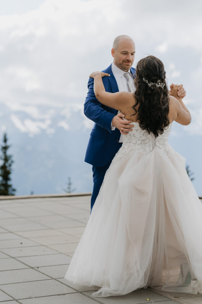 A bride and groom practice their first dance with a view of Mt. Rainier National Park in the background. 