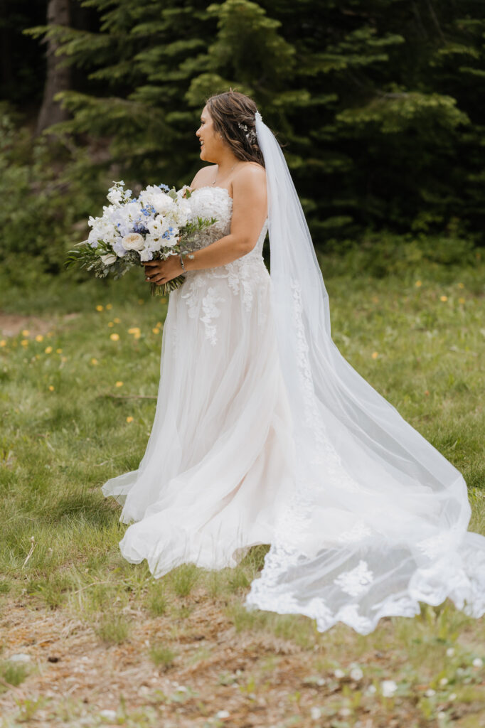 A bride smiles while holding her wedding day bouquet on her wedding day at Crystal Mountain.