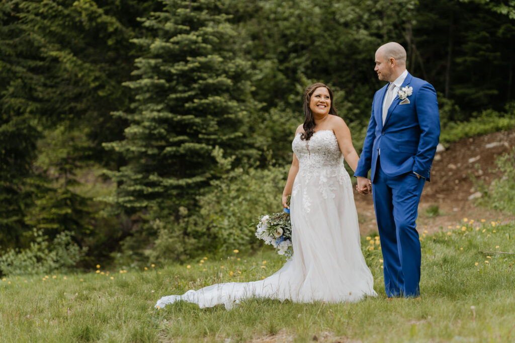 A bride and groom hold hands while smiling at each other on their wedding day at Crystal Mountain Resort. 