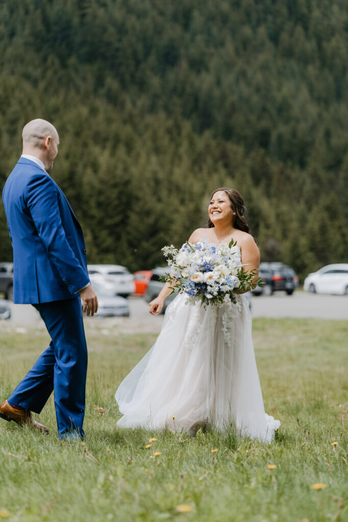 A bride and groom smile at each other during their first look on their wedding day near Mt. Rainier National Park.