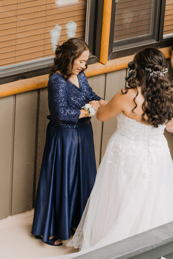 A bride's mom helps her get ready for her wedding day on the balcony of their condo room at Crystal Mountain Resort.