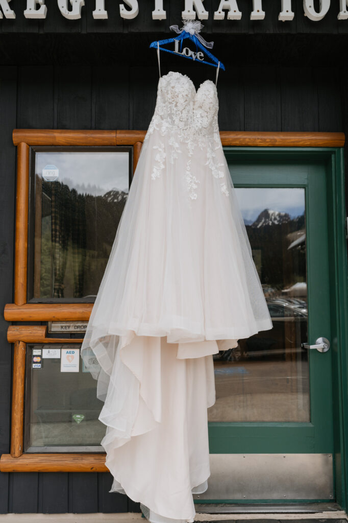 A wedding dress hanging from a blue hanger at the base of Crystal Mountain Resort. 