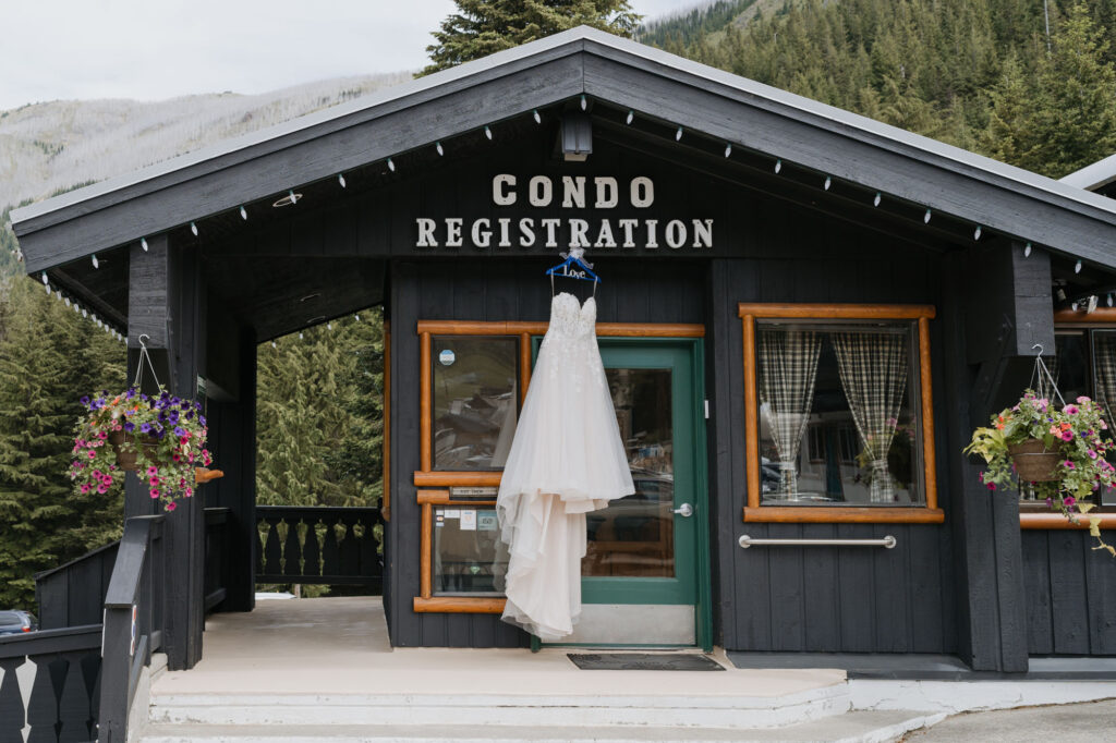 A wedding dress hanging from a cabin painted black. The cabin is located at Crystal Mountain Resort where this small wedding took place.