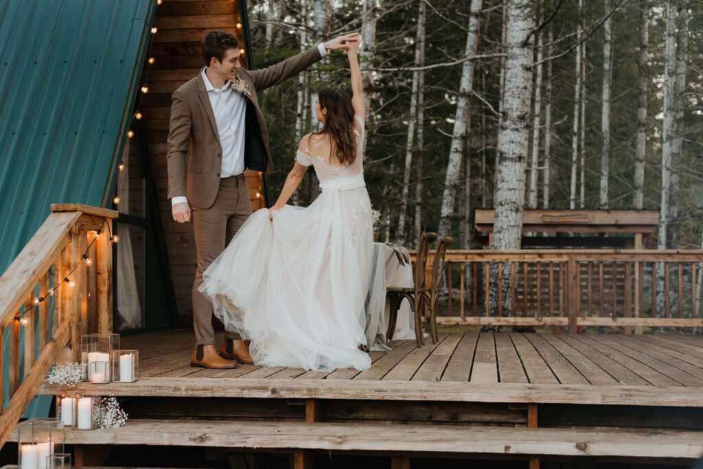 A groom twirling his bride on the deck of a cabin in Washington