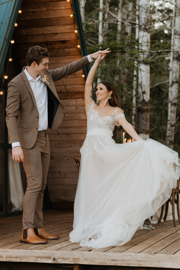 A groom twirling his bride on the deck of a cabin in Packwood, WA