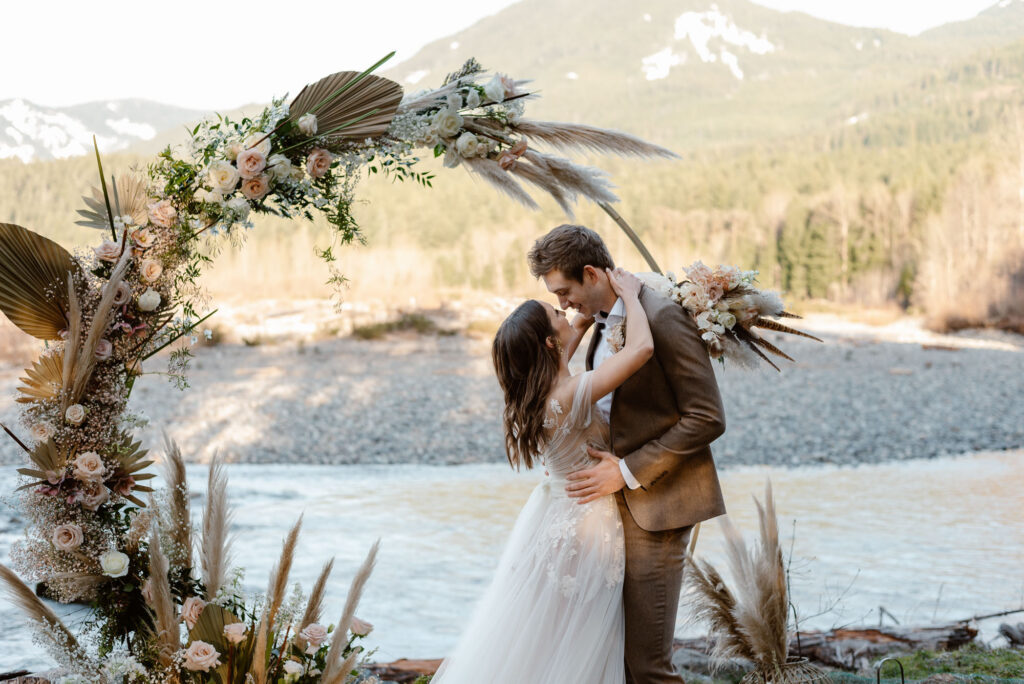 A couple embracing under a flower arch along the river in Washington