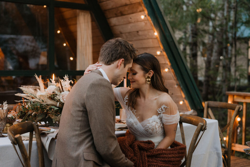 A cabin elopement near Mt. Rainier National Park. The couple is embracing each other while sitting down in front of a cabin. 