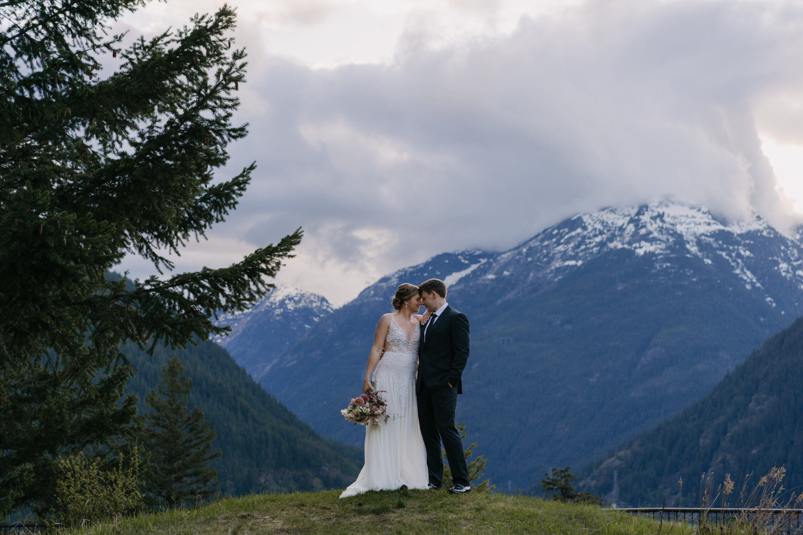 North Cascades Elopement with a couple in wedding attire standing in front of the mountains.