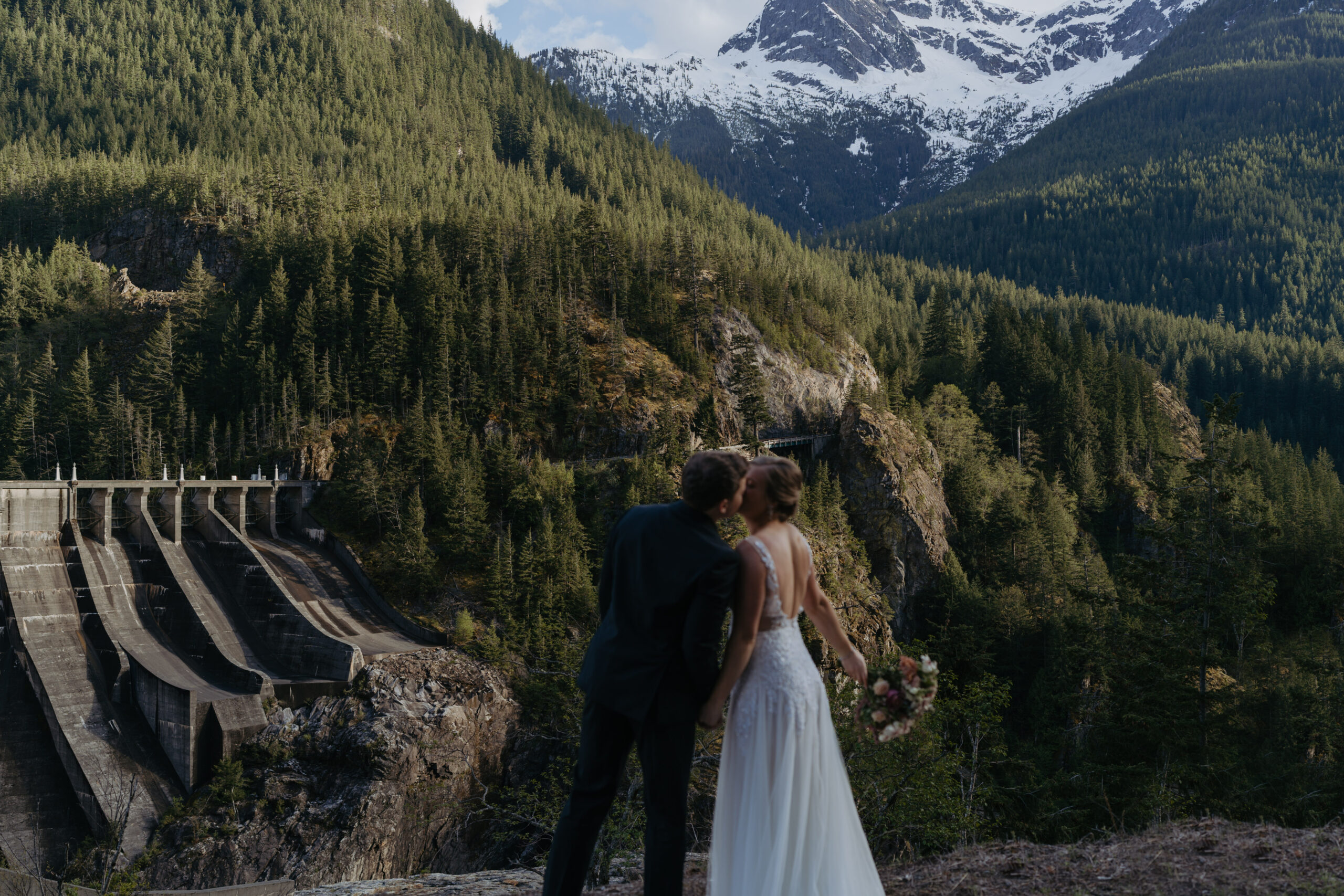 A couple eloping in the north cascades of Washington state. They are kissing with a view of the mountains in the background.